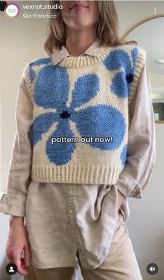 a woman wearing a sweater with blue flowers on it