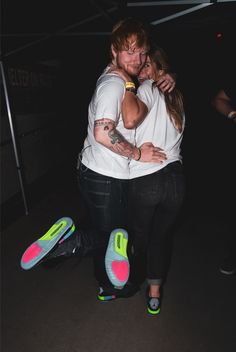 a man and woman hugging in the dark with their feet on each other's shoulders