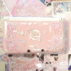 a pink tablet with stickers on it sitting on top of a table next to other items