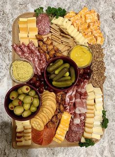 an assortment of cheeses, meats and vegetables on a platter with olives