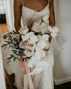 a woman holding a bouquet of flowers in her hand and wearing a white wedding dress