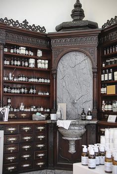 an old fashioned pharmacy cabinet with lots of bottles on the shelves and in front of it is a sink