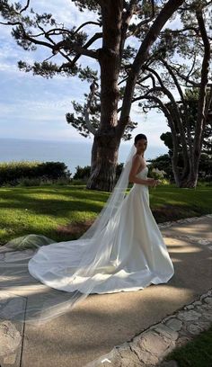 a woman in a wedding dress standing next to a tree