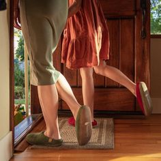 two women in slippers are standing at the front door