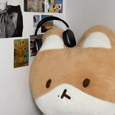 a brown and white stuffed animal with headphones on it's ears next to a wall