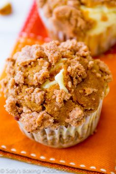 a close up of a muffin on an orange napkin with other food items in the background