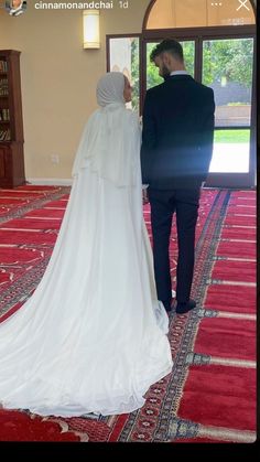 the bride and groom are looking at each other in front of an open door with red carpet