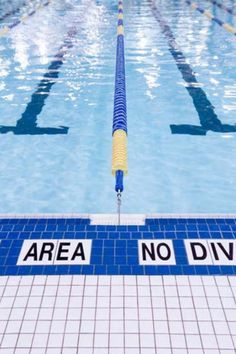 an empty swimming pool with no diving signs on the side and blue tile around it