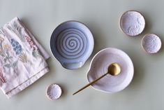 three bowls and two spoons are sitting on the table next to each other, one has a gold spoon in it