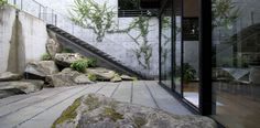 an outdoor area with rocks and plants next to a stair case that leads up to the second floor