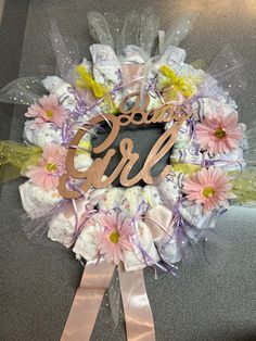 a wreath with the word baby girl written on it and flowers in front of it