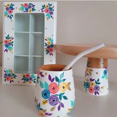 two vases with flowers painted on them are next to a wooden spoon and shelf