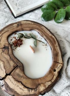 a candle is sitting on top of a piece of wood next to an open book