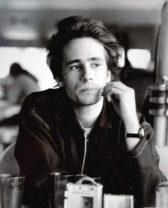 a black and white photo of a man sitting at a table with drinks in front of him