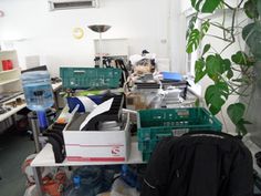 a room filled with lots of clutter next to a green potted plant on top of a table