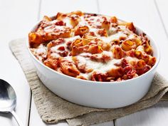 a casserole dish with meat and cheese on a napkin next to a spoon