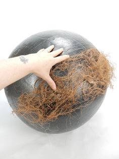 a person's hand on top of a large ball with some brown stuff in it