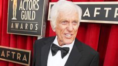 an older man in a tuxedo and bow tie posing for a photo on the red carpet