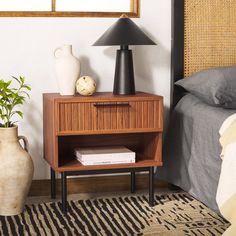 a nightstand with a lamp on top of it next to a bed and a rug