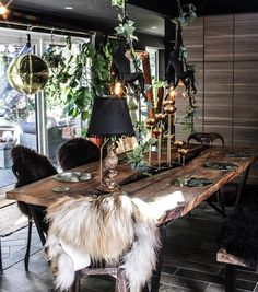 a wooden table topped with lots of plants next to a wall filled with hanging lights