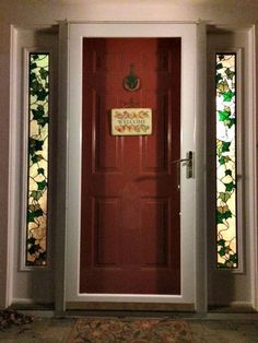 a red front door with stained glass windows and a welcome sign on it's side