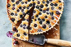 a blueberry pie on a cutting board with a knife