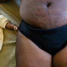 a baby in a diaper is standing next to a woman's stomach and belly