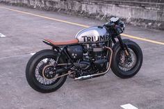 a triumph motorcycle parked on the side of the road in an empty parking lot with no one around it