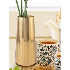 a vase with some flowers in it next to two cups and a teapot on a table