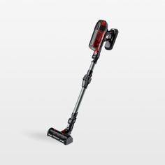 a red and black cordless stick vacuum on a white surface with the handle extended