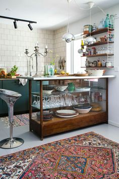 a kitchen filled with lots of clutter and dishes on top of a counter next to a rug