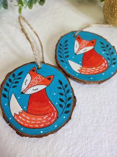 two wooden ornaments with red foxes on them