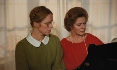 two women sitting next to each other in front of a piano