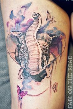 an elephant tattoo on the leg of a woman's thigh with butterflies around it