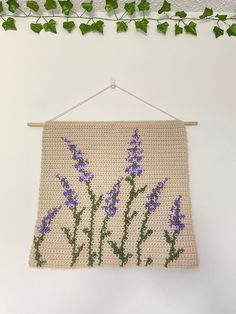 a crocheted wall hanging with purple flowers