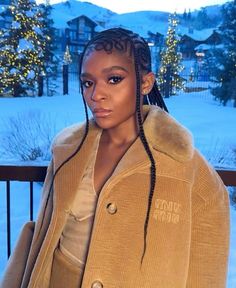 a woman with braids standing in front of snow covered mountains and trees at night