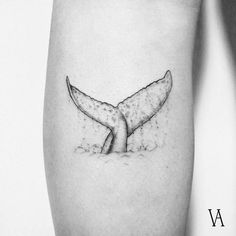 a black and white photo of a whale's tail tattoo on the right thigh