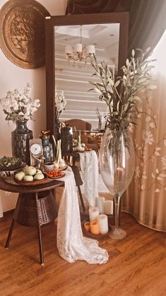 a table with flowers and candles on it in front of a mirror