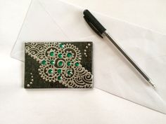 a pen and some paper on top of a white envelope with an intricately designed design