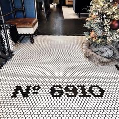 a black and white tiled floor with the word coco written on it next to a christmas tree