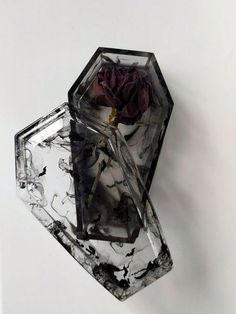 a rose sitting inside of a crystal box on top of a white table next to a wall