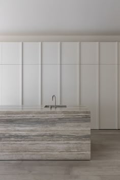 an empty kitchen with marble counter tops and white cupboards on the wall behind it