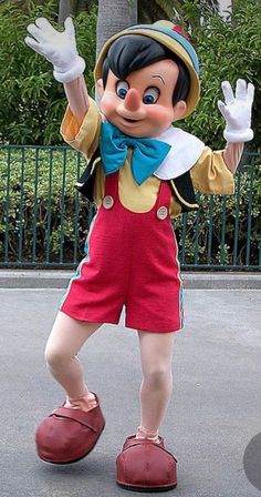 a mickey mouse mascot standing in the middle of a street with his arms up and hands out