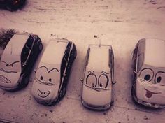 four cars with faces drawn on them are lined up in a row