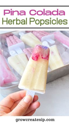 a hand holding an ice cream popsicle with pink and white toppings in it