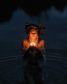 a woman in the water holding a lit candle