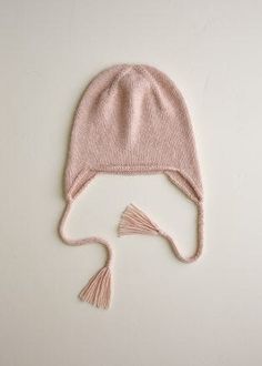 a pink knitted hat with tassels on top