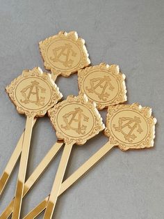 four gold pins with the letter a on them sitting in front of a gray background