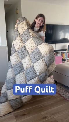 a woman sitting on top of a giant blanket in a living room next to a couch