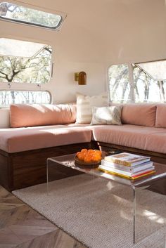 a living room filled with furniture and pillows on top of a wooden floor next to windows